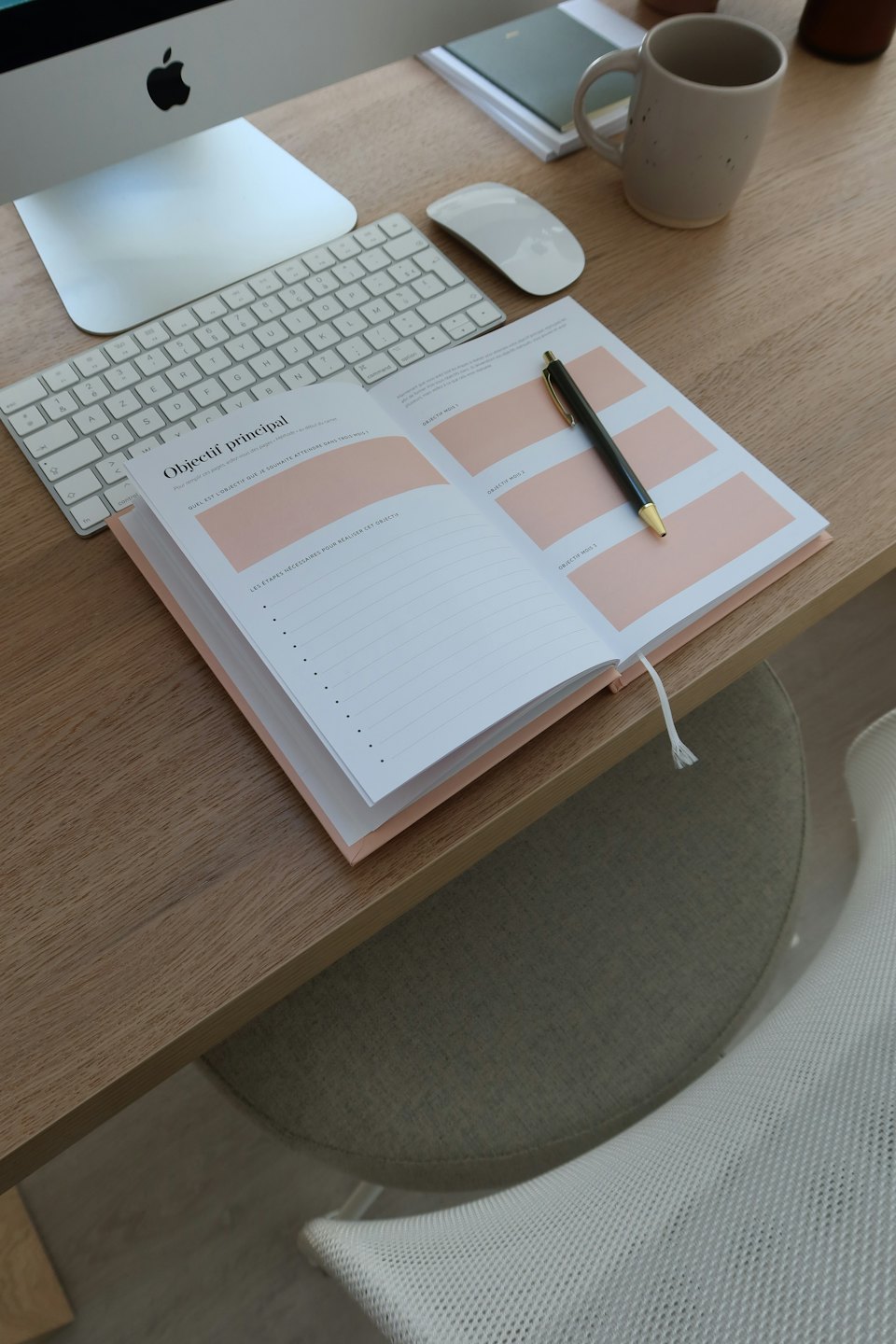 Ein offener Planer und ein Stift liegen auf einem hölzernen Büroschreibtisch.